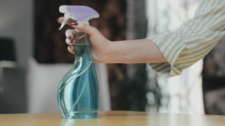A womans hand puts a bottle of detergent on the table.の写真素材