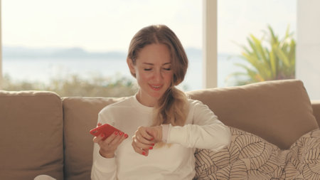 Happy woman using smart phone for downloading mobile app in home interiorの写真素材