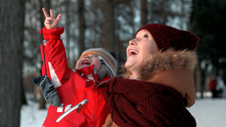Happy young mother and toddler son smiling walking in winter parkの写真素材