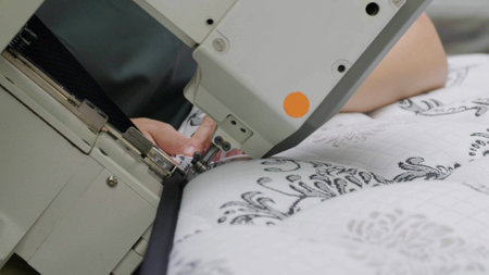 Woman sewing textile on a sewing machine. Manufacturing in a factory.Close upの写真素材