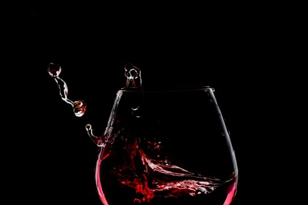 Splash of wine in the glass on dark backroundの写真素材