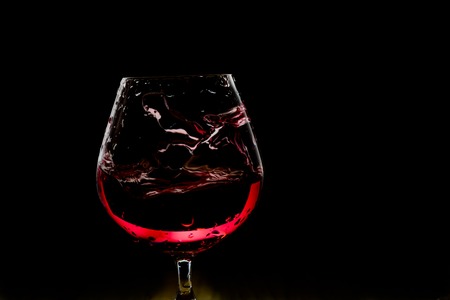 Splash of wine in the glass on dark backroundの写真素材