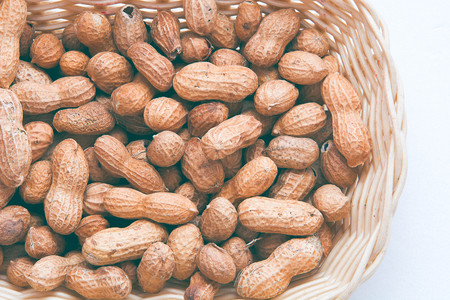 Peanut in the basket on white background made up of salted peanuts in their shellsの写真素材
