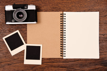 Blank notebook and photo frames with camera on wooden background.の写真素材