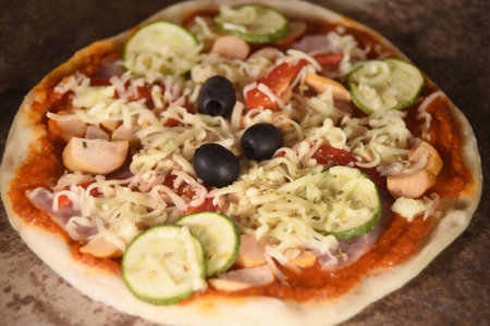 Cheese on a freshly prepared pizza on wooden board.の写真素材