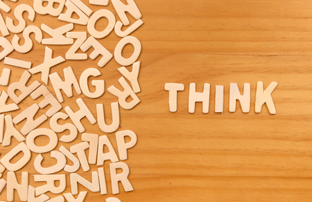 Word think made with block wooden letters next to a pile of other letters over the wooden board surface compositionの写真素材
