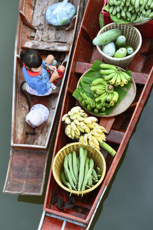 AMPHAWA ? APRIL 29: Wooden boats are loaded with fruits from the orchards at Tha kha floating market on April 29, 2015 in Amphawa. A traditional way still practiced in Tha kha canals of Thailand.のeditorial素材