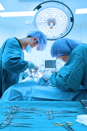 two veterinarian surgeons in operating room take with art lighting and blue filterの写真素材