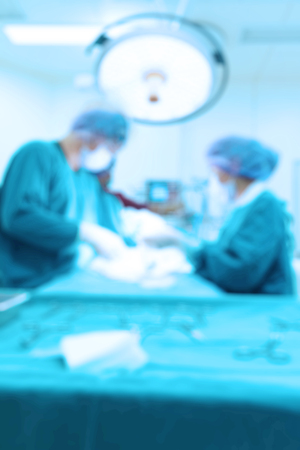 Blur of two veterinarian surgeons in operating room take with art lighting and blue filterの写真素材