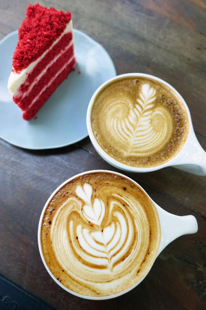 cup of latte art coffee and cake on wood tableの写真素材