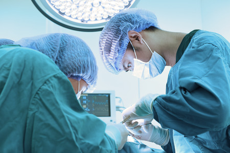 two veterinarian surgeons in operating room take with art lighting and blue filterの写真素材