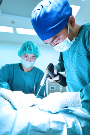 two veterinarian surgeons in operating room take with art lighting and blue filterの写真素材