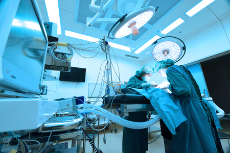 two veterinarian surgeons in operating room take with art lighting and blue filterの写真素材