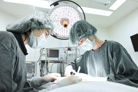 two veterinarian surgeons in operating room take with selective color technique and art lightingの写真素材