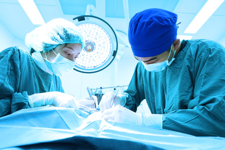 two veterinarian surgeons in operating room take with art lighting and blue filterの写真素材