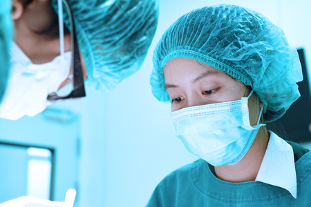 two veterinarian surgeons in operating room take with art lighting and blue filterの写真素材