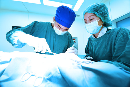 two veterinarian surgeons in operating room take with art lighting and blue filterの写真素材