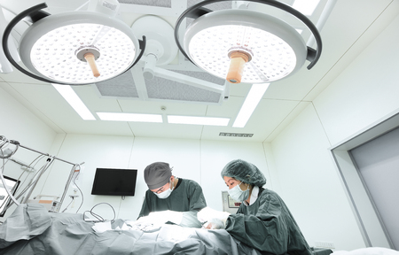 two veterinarian surgeons in operating room take with selective color technique and art lightingの写真素材
