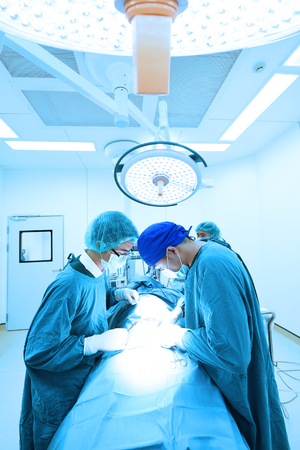 two veterinarian surgeons in operating room take with art lighting and blue filterの写真素材