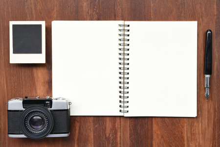 Blank paper with pen, photo frames and camera on wooden background.の写真素材
