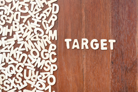 Word target made with block wooden letters next to a pile of other letters over the wooden board surface compositionの写真素材