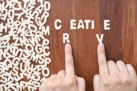 Word creative made with block wooden letters next to a pile of other letters over the wooden board...