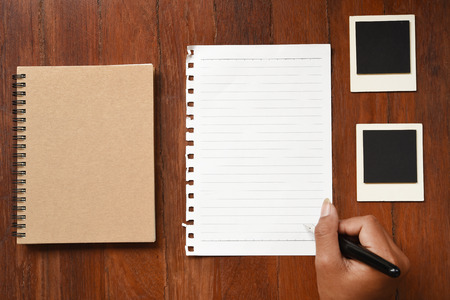 Blank notebook with photo frames and pen on hand for backgroundの写真素材