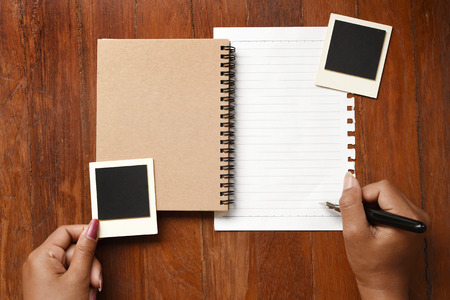 Blank notebook with photo frames and pen on hand for backgroundの写真素材