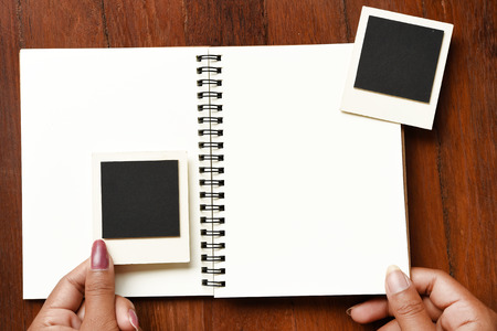 Blank notebook and photo frames on hand for backgroundの写真素材
