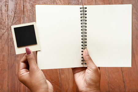 Blank notebook and photo frames on hand for backgroundの写真素材