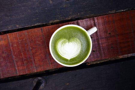 A cup of green tea matcha latte on wooden background
