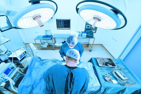two veterinarian surgeons in operating room take with art lighting and blue filterの写真素材