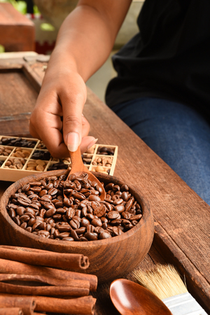 Freshly ground coffee beans in a metal filter and different coffee beans in a square box with coffee beans in bowlの写真素材