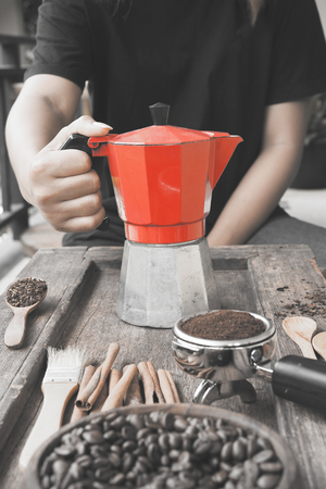 Freshly ground coffee beans in a metal filter and coffee beans in bowl with red kettle on the side take with selective color technique and art lightingの写真素材