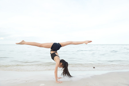 little girl doing gymnast on the beachの写真素材