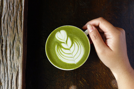 A cup of green tea matcha latte on wooden backgroundの写真素材