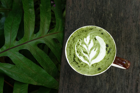 A cup of green tea matcha latte on wooden backgroundの写真素材