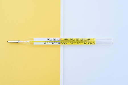 medical thermometer on yellow and white background