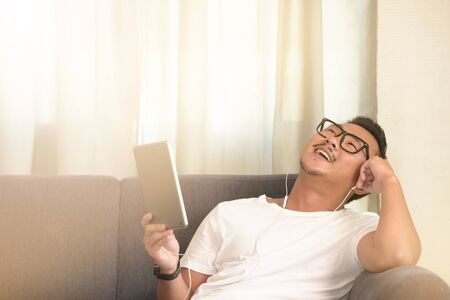 Man relaxing at home on the couch and using tablet