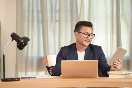 Portrait of young man sitting at his desk in the officeの写真素材