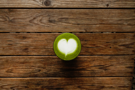 A cup of green tea matcha latte on wooden backgroundの写真素材