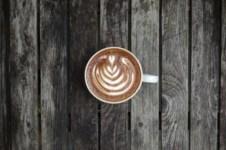 a cup of latte art coffee on wooden backgroundの写真素材