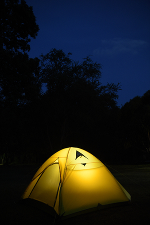 Illuminated yellow camping tent at nightの写真素材