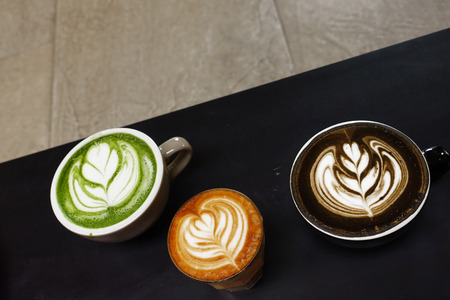 A cup of green tea matcha latte and cup of latte art coffee on wooden backgroundの写真素材