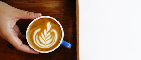a cup of latte art coffee on wooden background