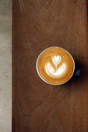a cup of latte art coffee on wooden backgroundの写真素材