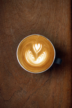 a cup of latte art coffee on wooden backgroundの写真素材