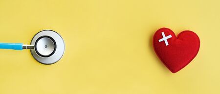 Red heart with stethoscope on yellow background