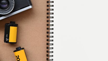 close up of notebook with photo film and camera isolated on white background