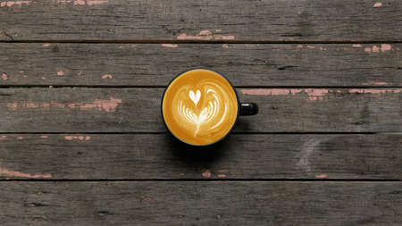 a cup of latte art coffee on wooden background